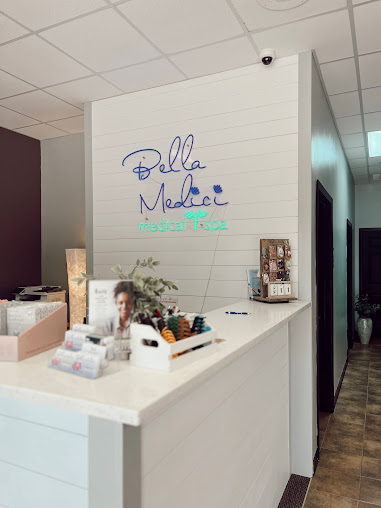 Reception desk at Bella Medici Medical Spa with a white counter holding skincare products and decorative plants.