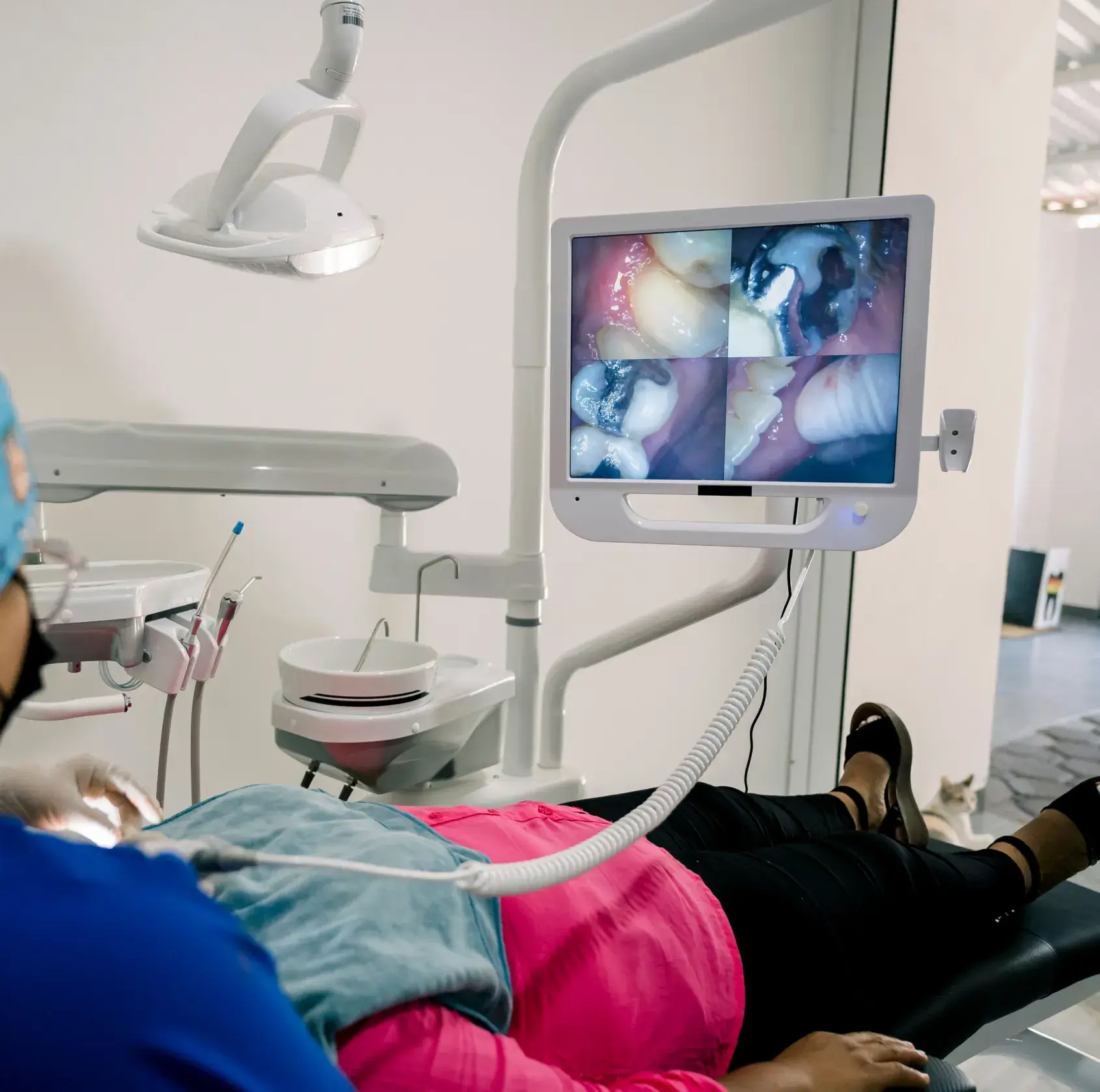 Dental patient lying back in chair with dentist viewing close-up images of teeth on monitor.