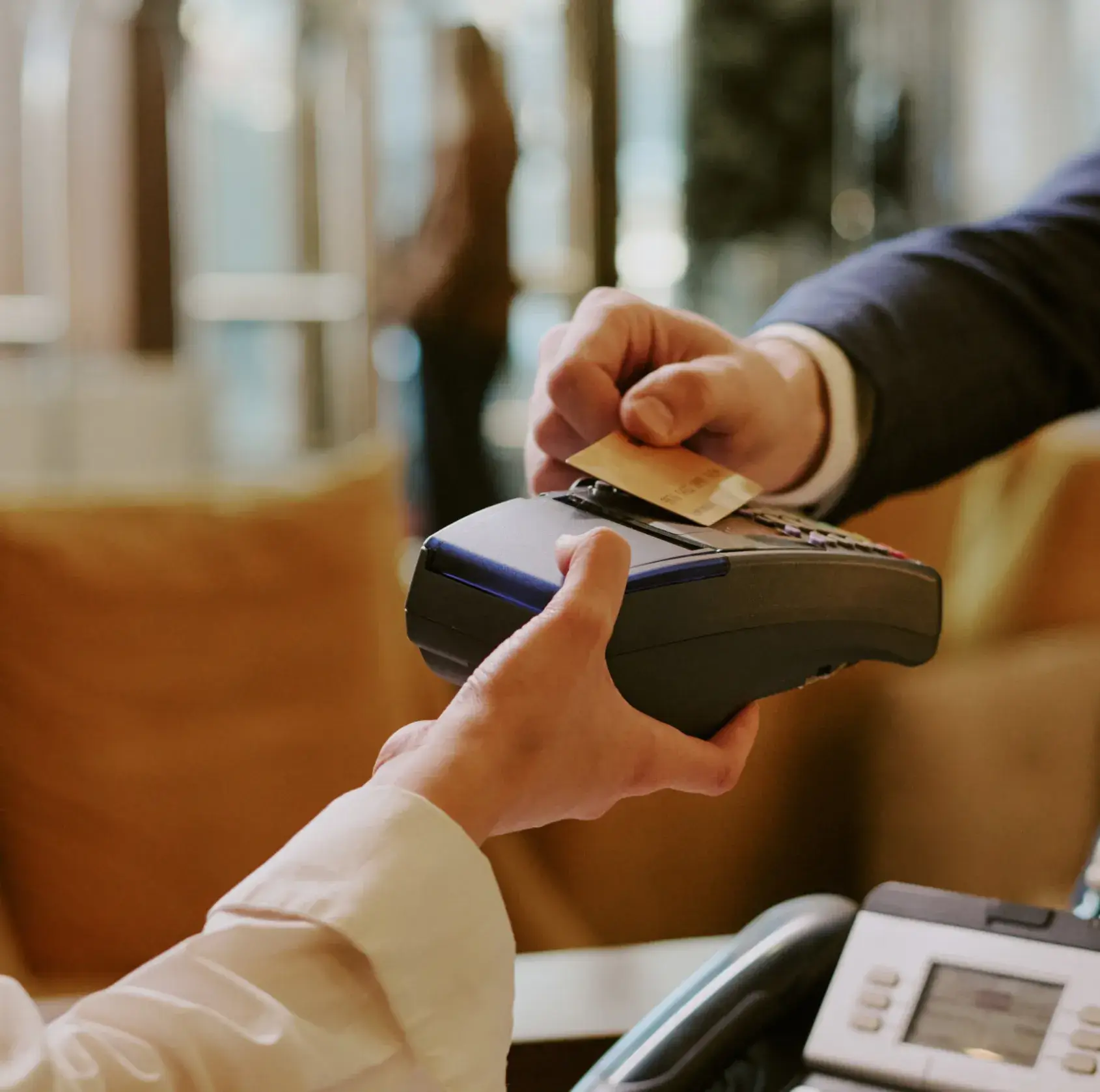Person using a contactless credit card on a payment terminal held by another person.