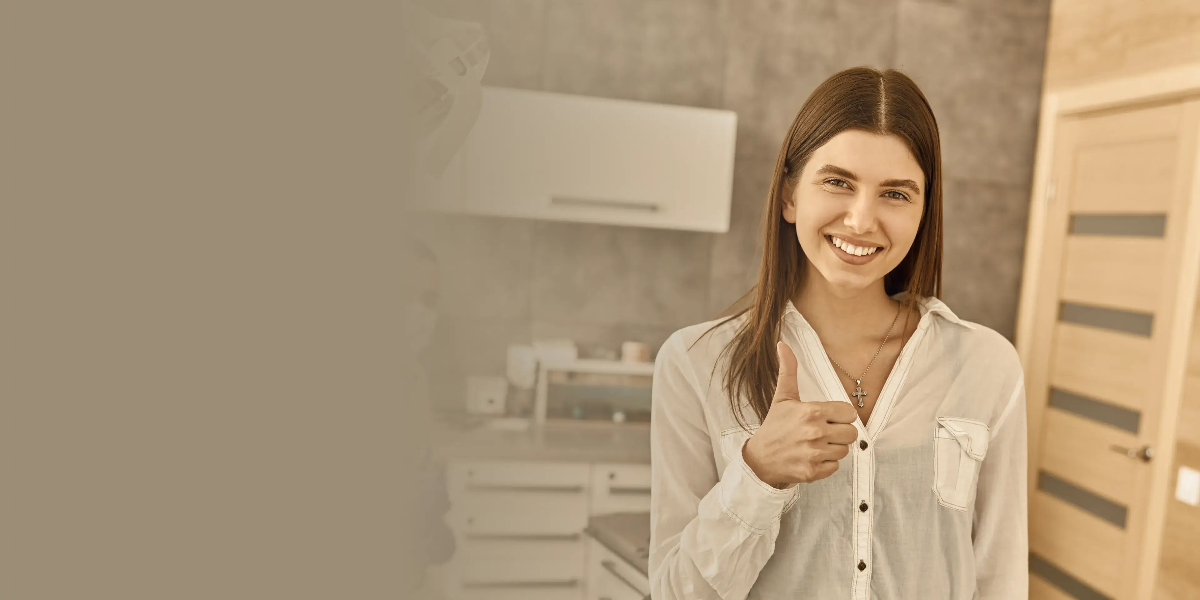 Smiling woman in a white shirt giving a thumbs-up inside a modern room with wooden doors.