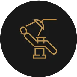 Icon of a reclining dental chair with overhead dental light in gold on a dark background.