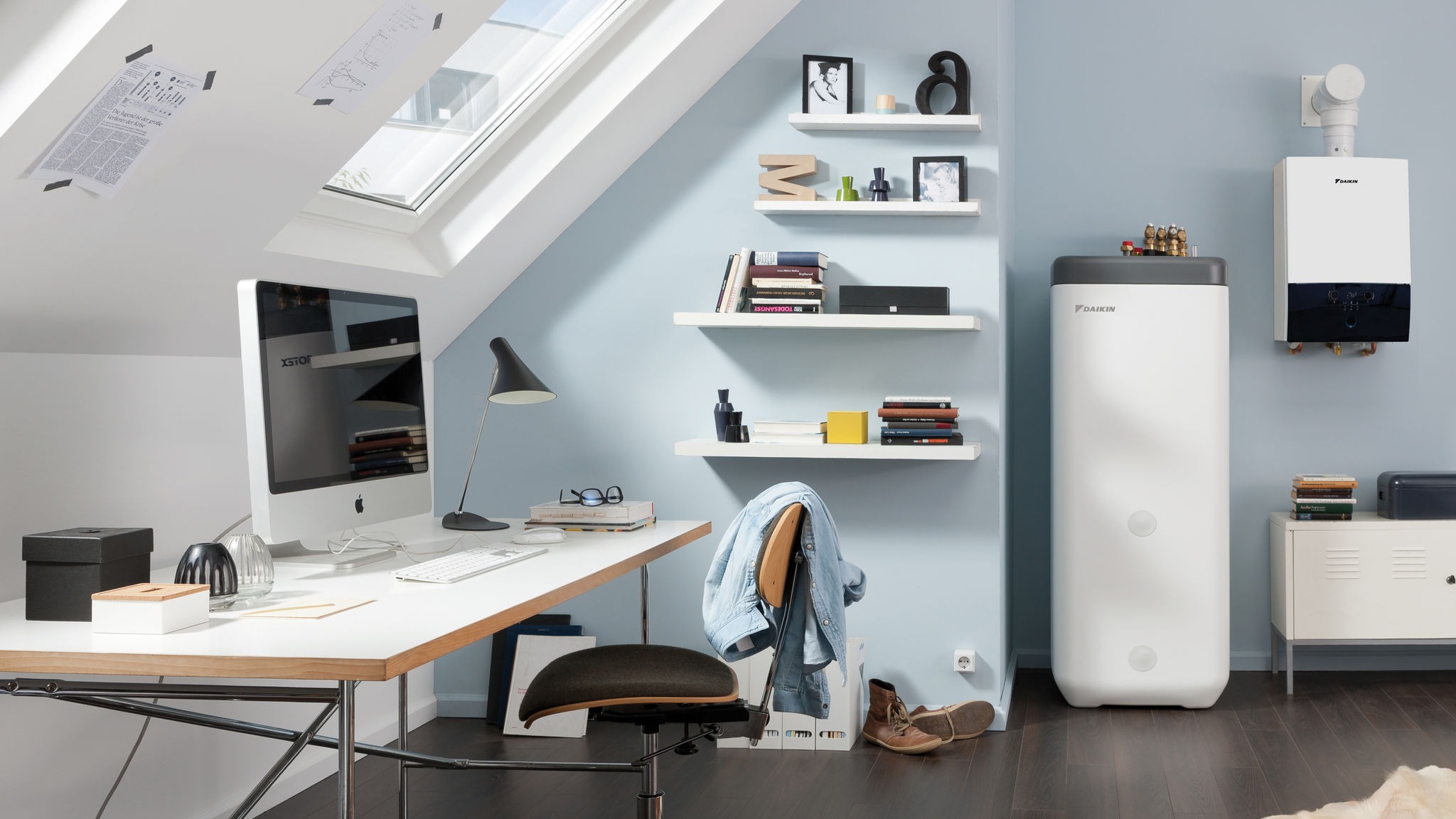 Modern home office with a white desk, iMac, black chair, shelves, and heating units on a blue wall.