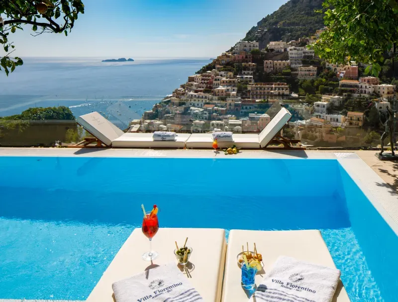 Infinity pool with lounge chairs and cocktails overlooking Positano and the sea