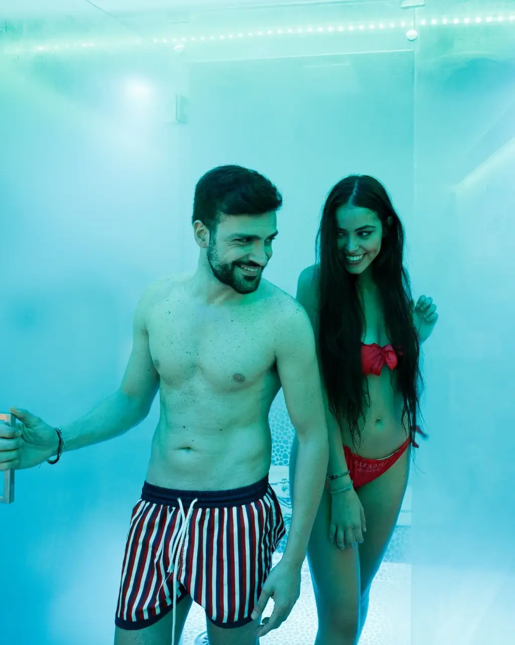 Couple relaxing in a heated pool lit by soft teal light at Villa Fiorentino at night