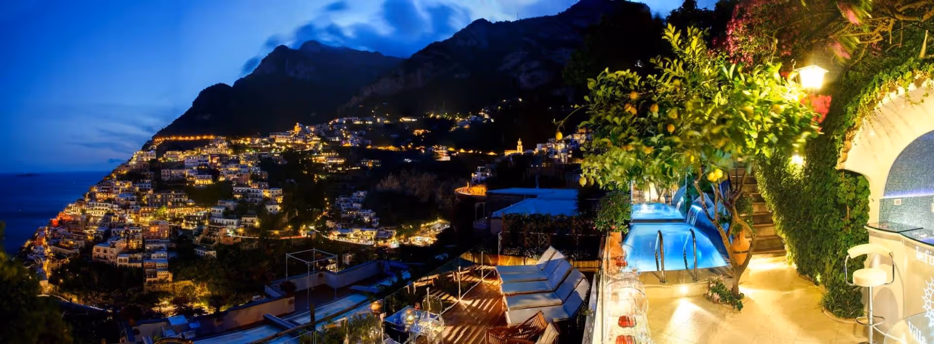 Villa Fiorentino's heated hydrotherapy pool illuminated at night above the lights of Positano