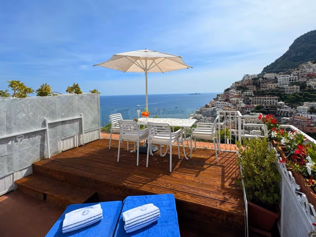 Terrace at Villa Fiorentino set for dining, overlooking the sea and the hillside town of Positano
