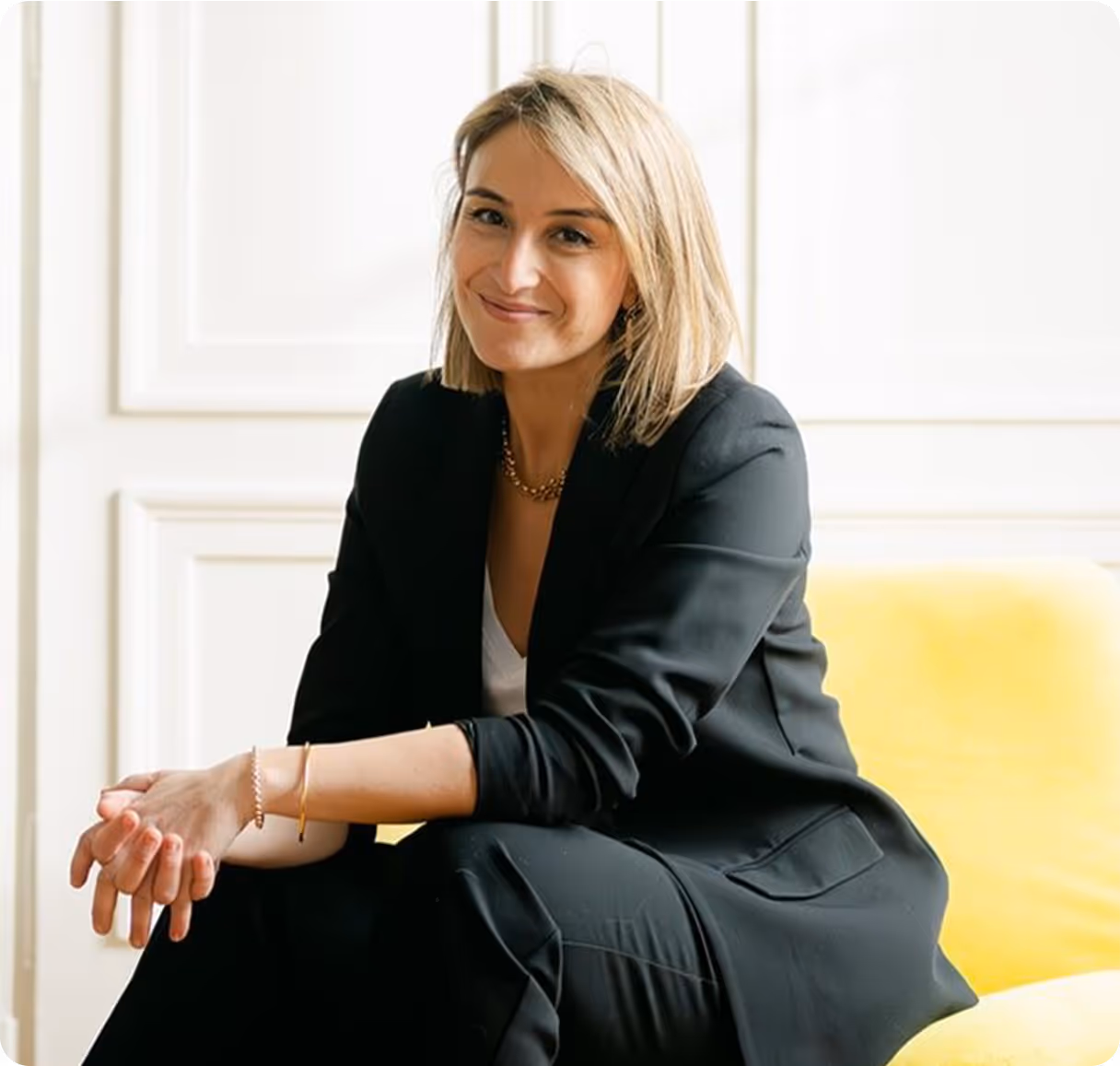 Samah, la fondatrice de l'application souriante assise dans un fauteuil jaune, incarnant confiance et leadership.