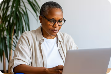 Femme concentrée travaillant sur un ordinateur portable dans un espace lumineux.