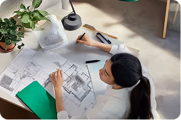 un plan de haut avec une femme qui travaille sur des plans