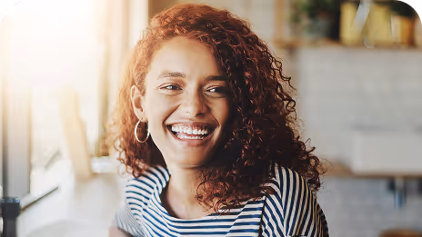 Femme rieuse profitant d’un moment de détente dans un café, symbolisant la confiance et la joie d’entreprendre.
