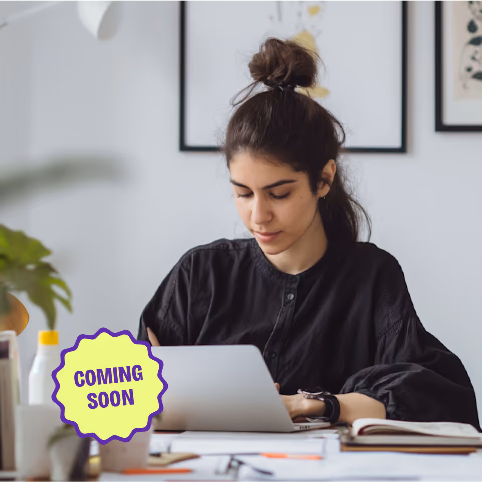 Femme concentrée écrivant sur un carnet avec ordinateur portable, vignette “Coming soon” à l’écran.