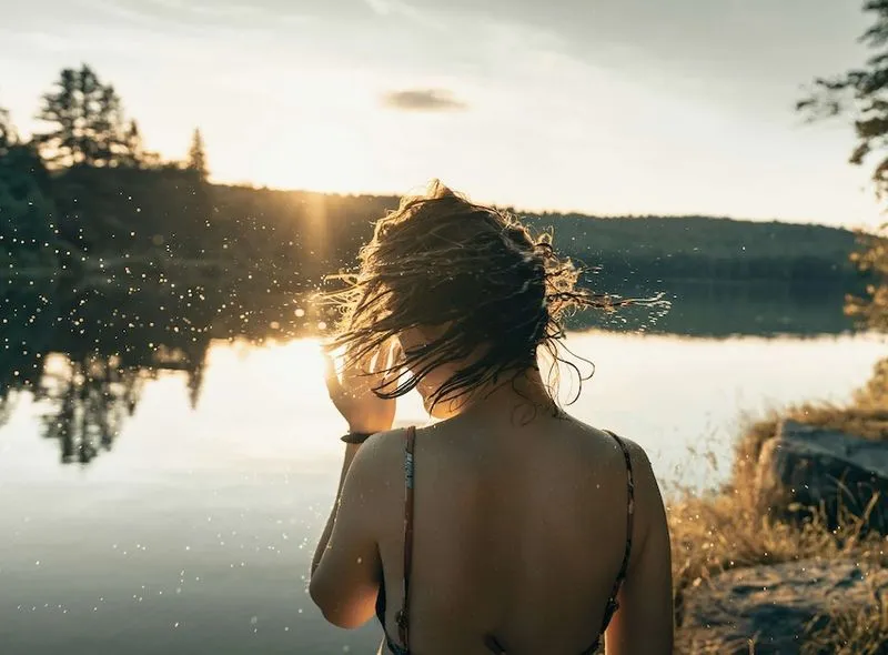 Women shaking the water off her at sunset