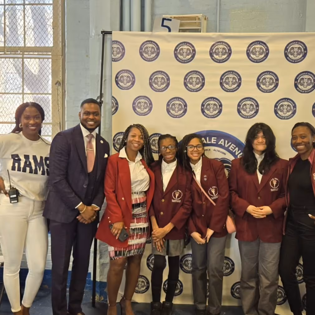 Students and staff posing in front of Riverdale Avenue Middle School banner