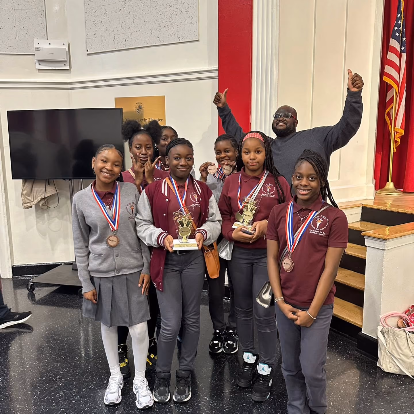 Students and coach celebrating third place trophies and medals at competition