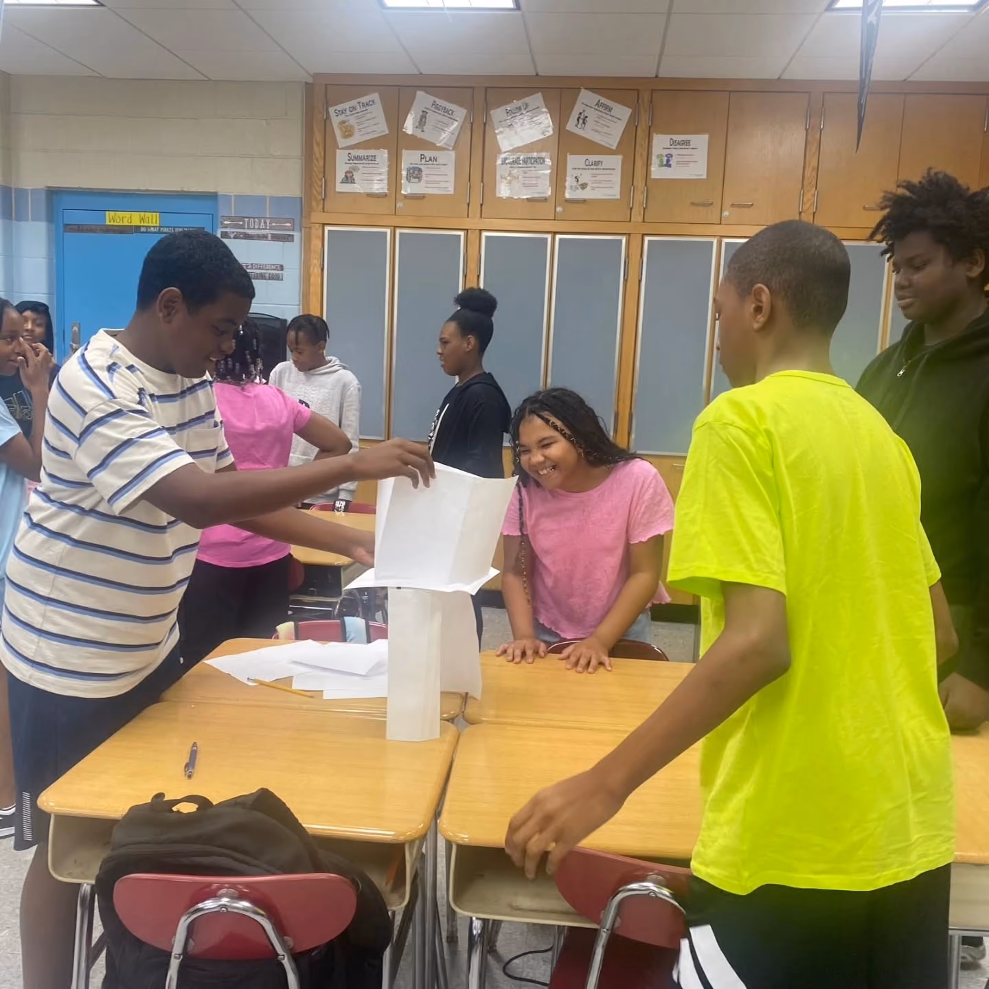 Students collaborating on a paper tower building activity in class