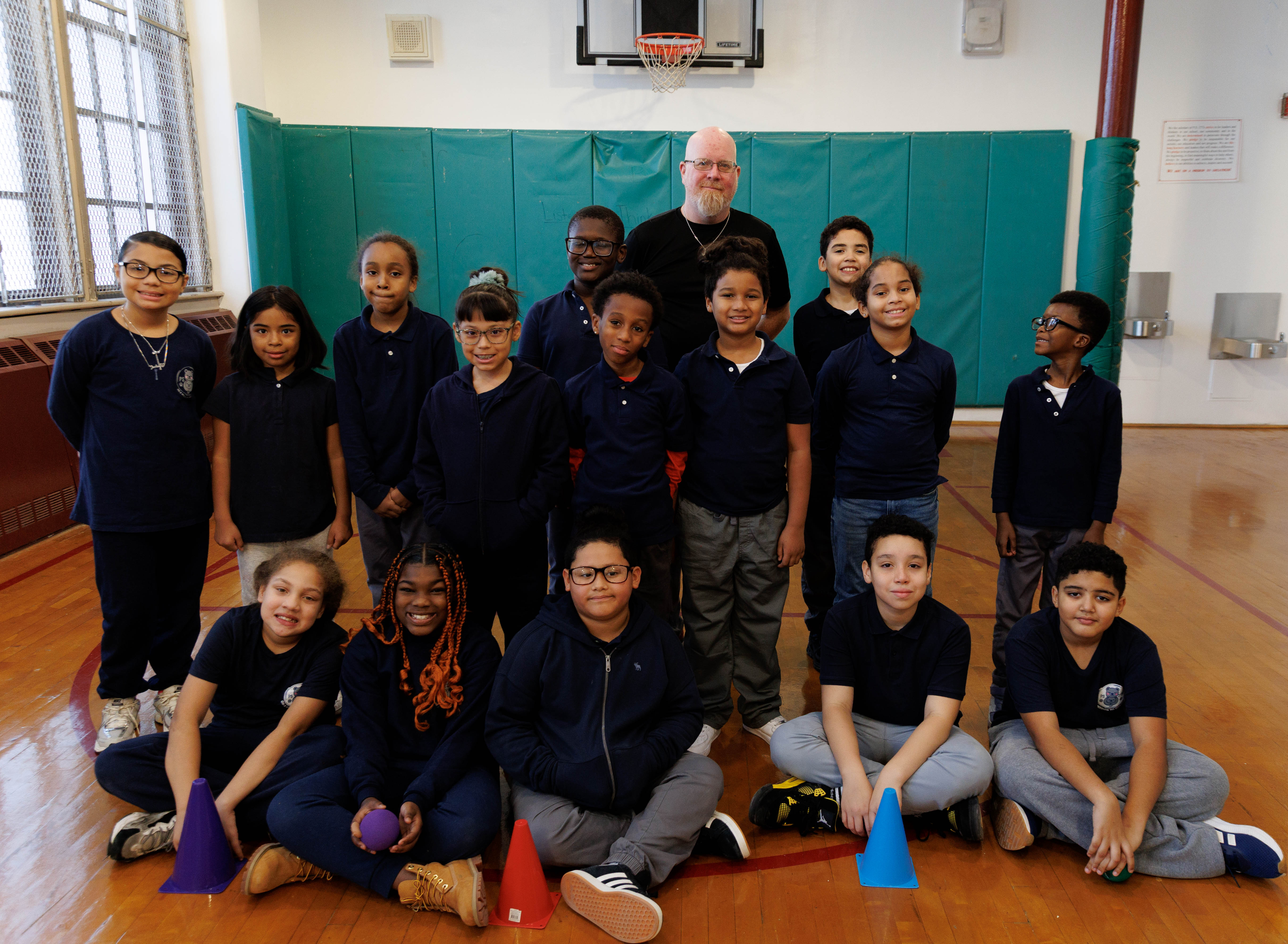 Students and physical education teacher posing together in school gymnasium