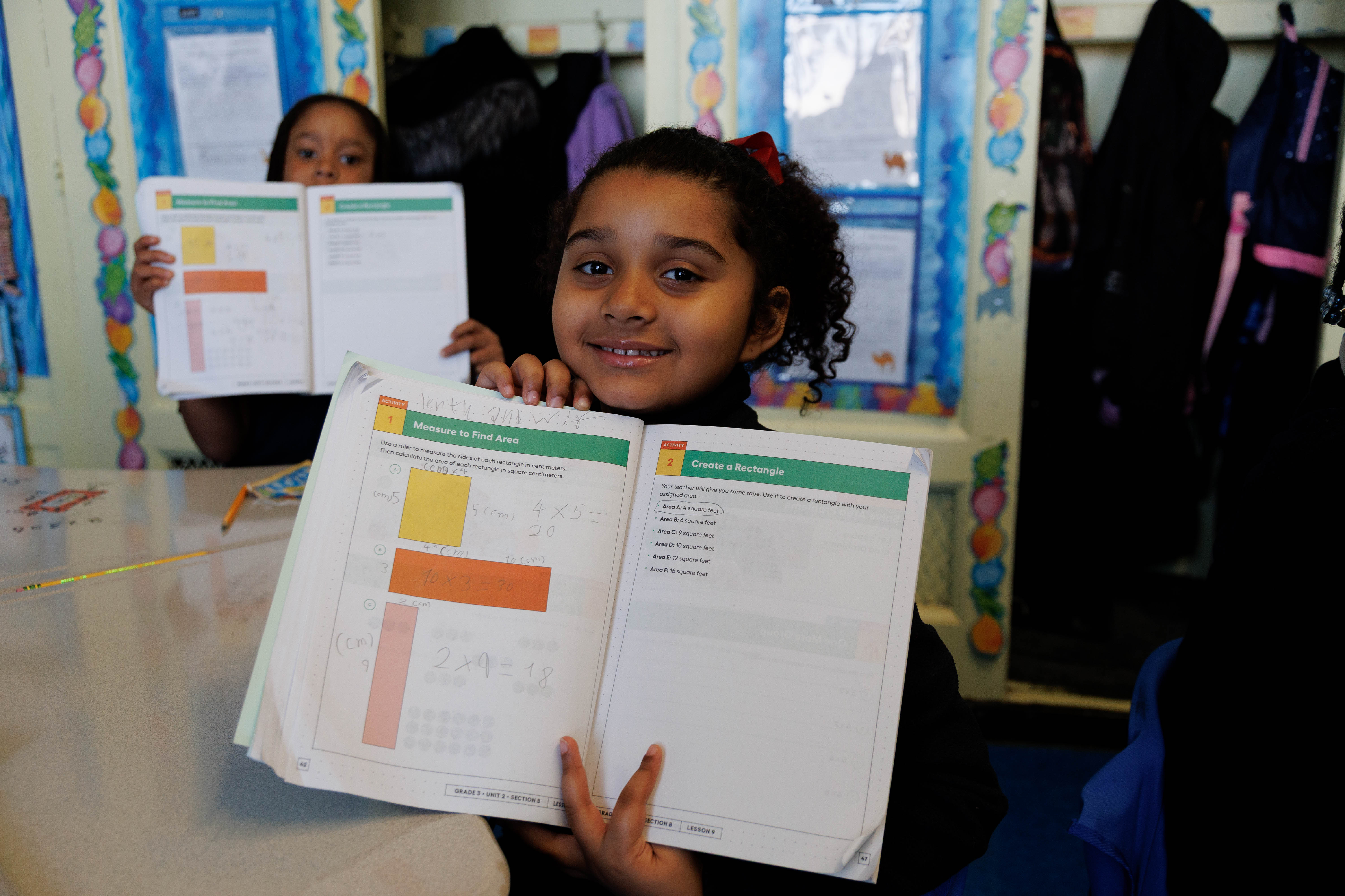 Student proudly showing completed math area worksheet to camera