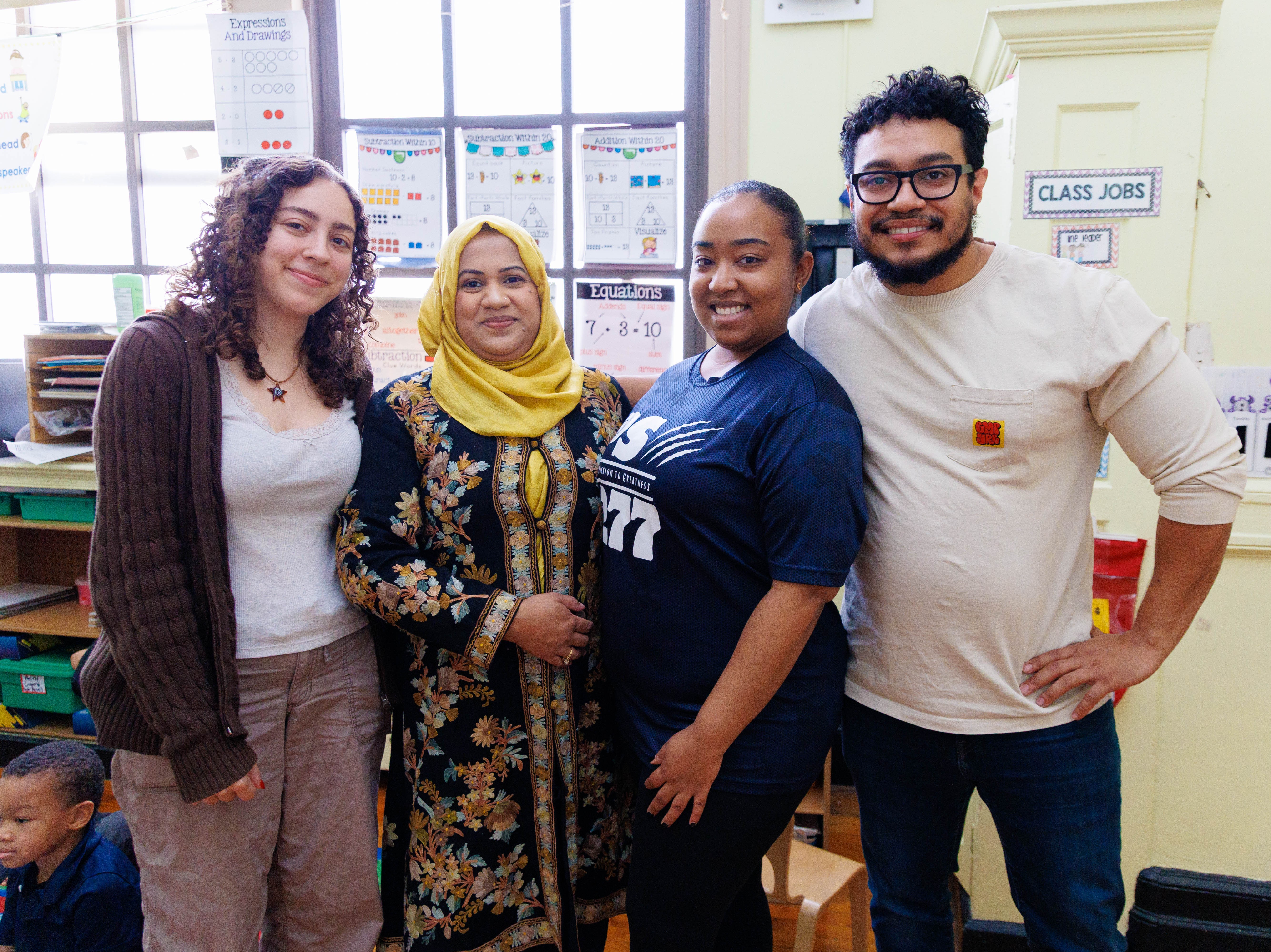 Four school staff members smiling together in an elementary classroom