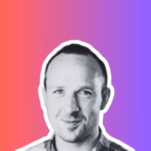 Black and white headshot of a smiling man with short hair against a red to purple gradient background.