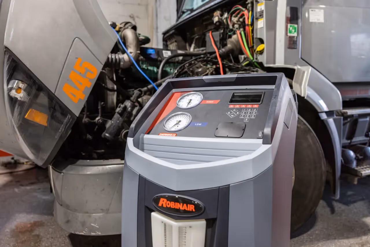 HVAC improve for winter service using a Robinair unit beside an open semi truck with visible engine components.
