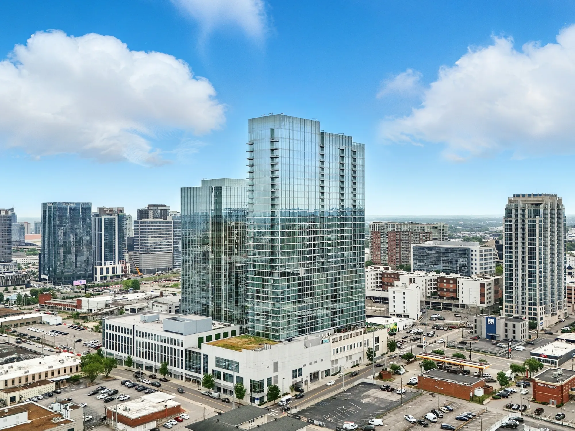 Cityscape of Nashville featuring modern glass skyscrapers under a partly cloudy blue sky.