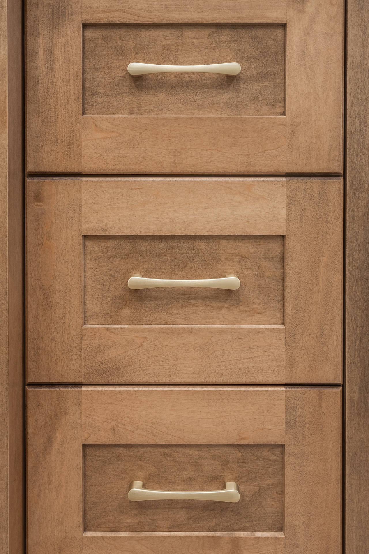 Close-up of three vertically stacked wooden drawers with beige handles by Marvel Cabinetry.