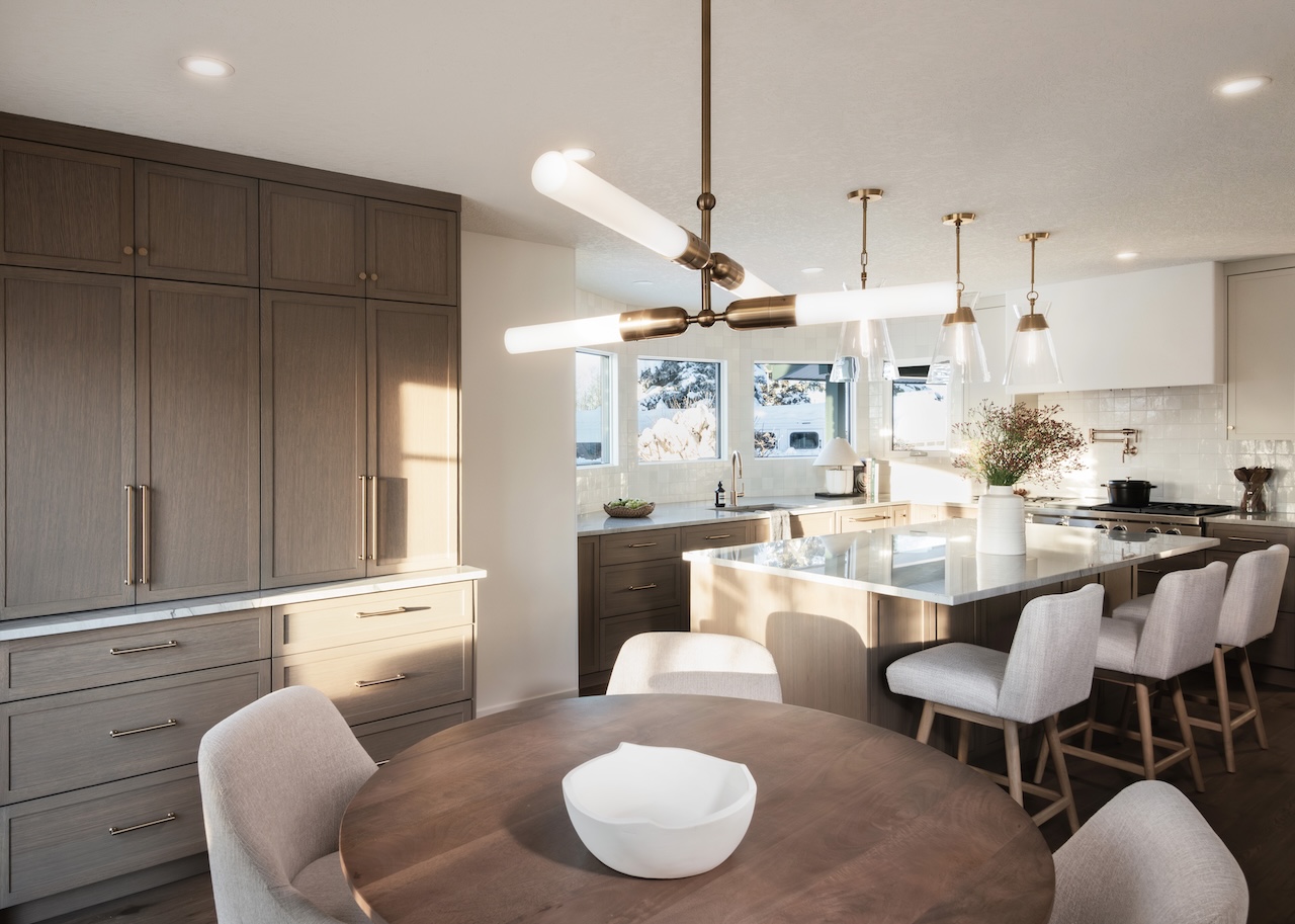 Open kitchen drawer with organized wooden cutlery tray holding rose gold utensils and measuring spoons under a white marble countertop by Marvel Cabinetry.