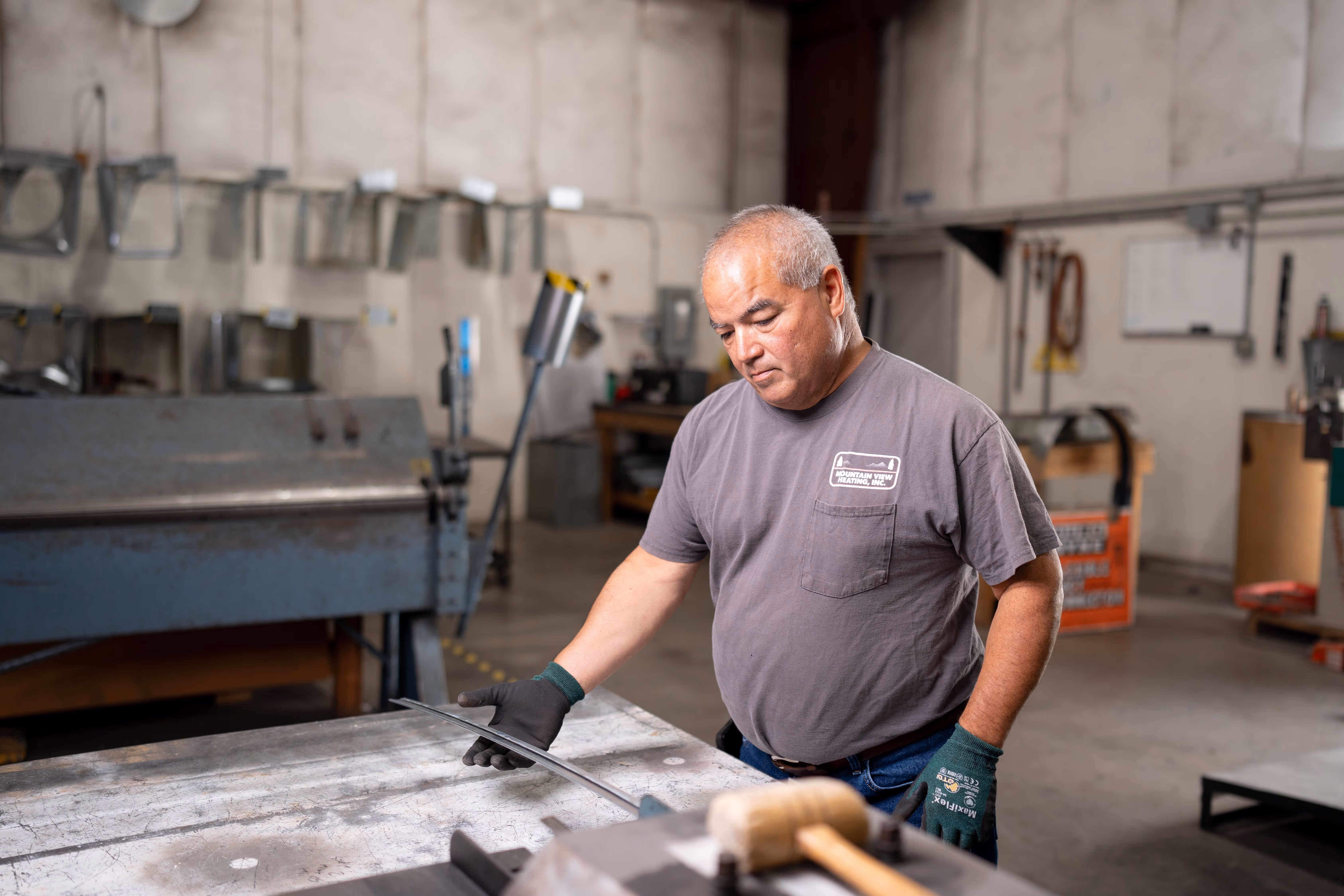 A man in a garage working on a piece of metal.