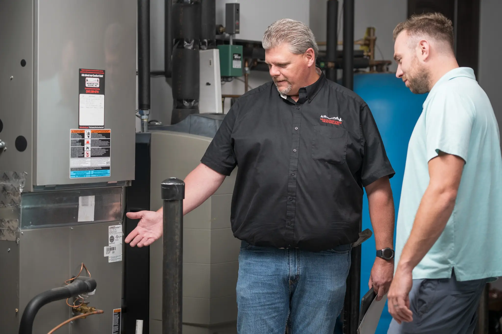 HVAC technician explaining furnace to customer.