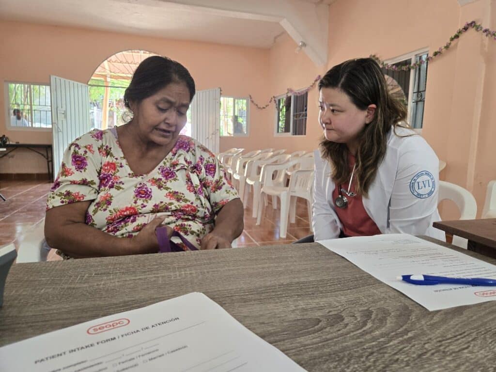 Christian doctor sitting with a patient in a medical missions outreach center in Oaxaca, Mexico.