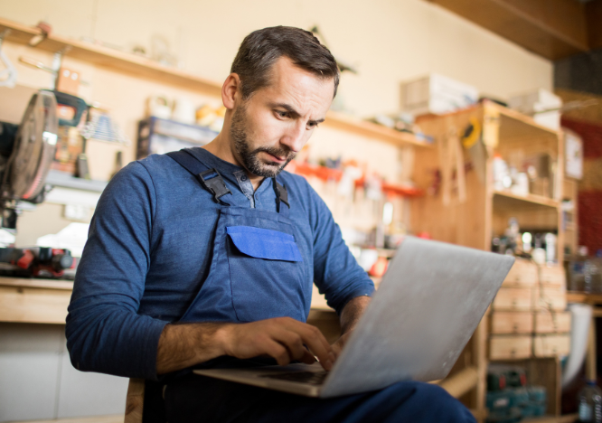 a shop owner works on his laptop promoting his business by engaging with the followers he has gained