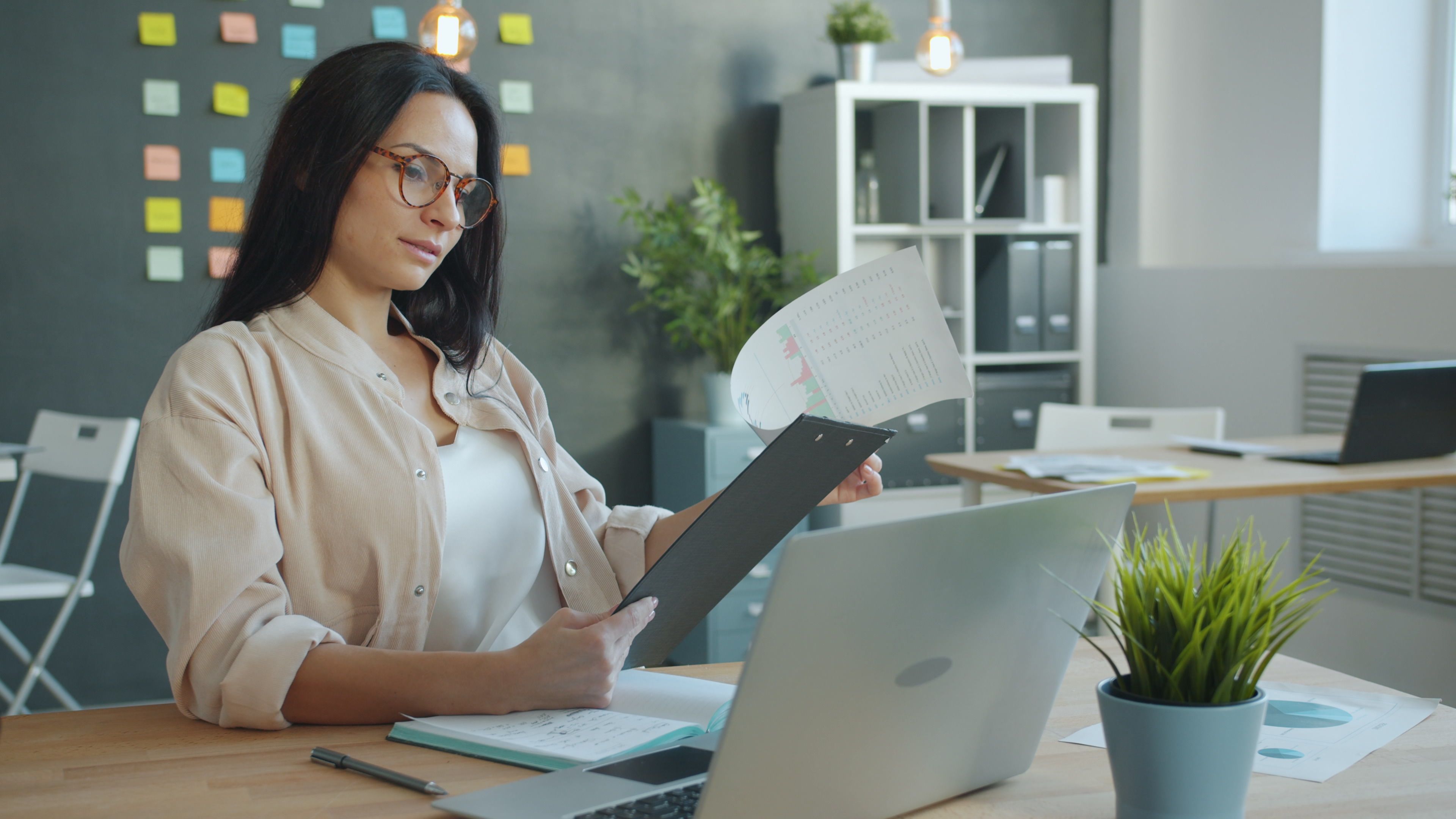A small business owner at a desk reviewing visual posts alongside a style guide to illustrate how fixing inconsistent messaging builds a recognizable brand presence.