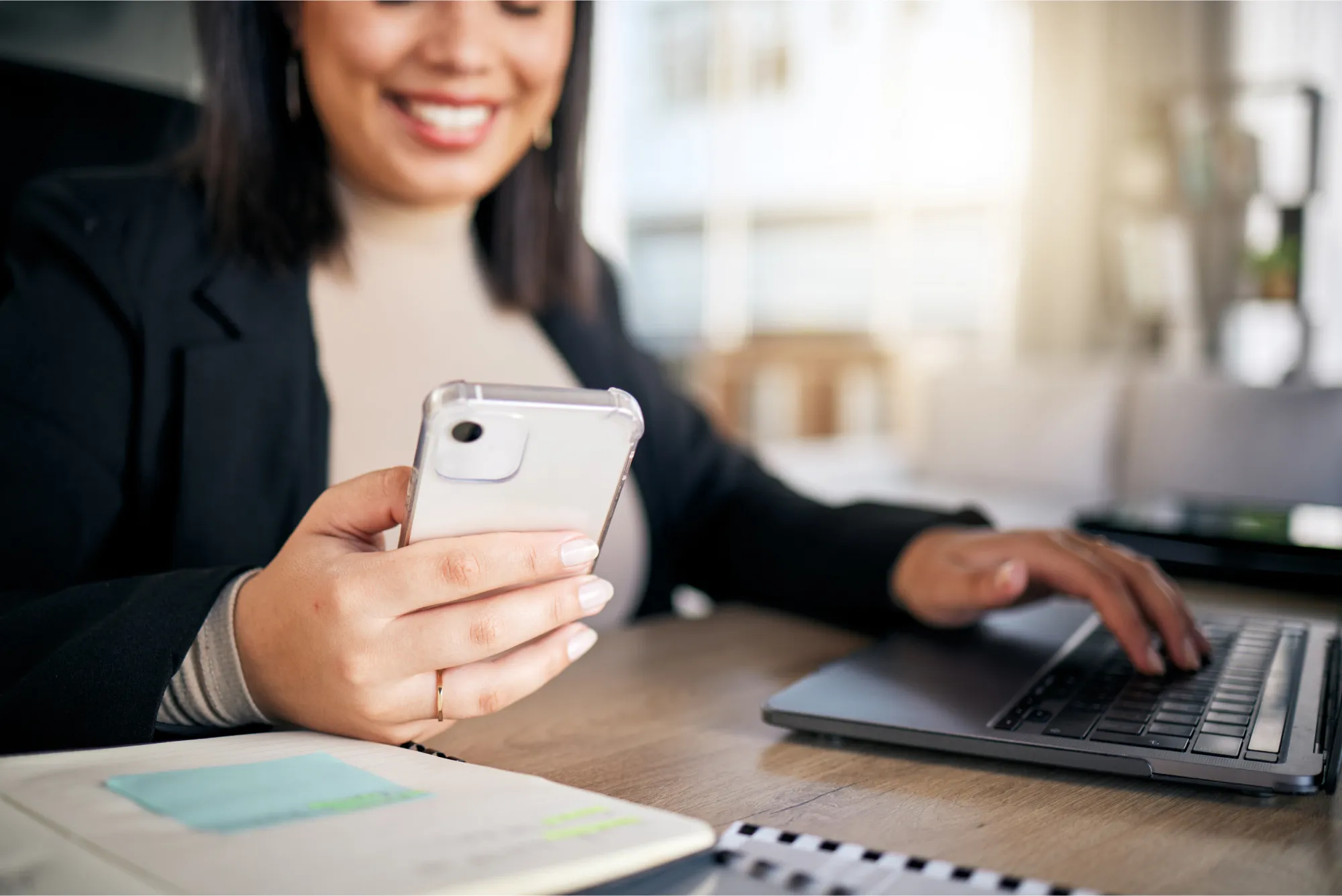 A woman sitting at a desk using a cell phone.