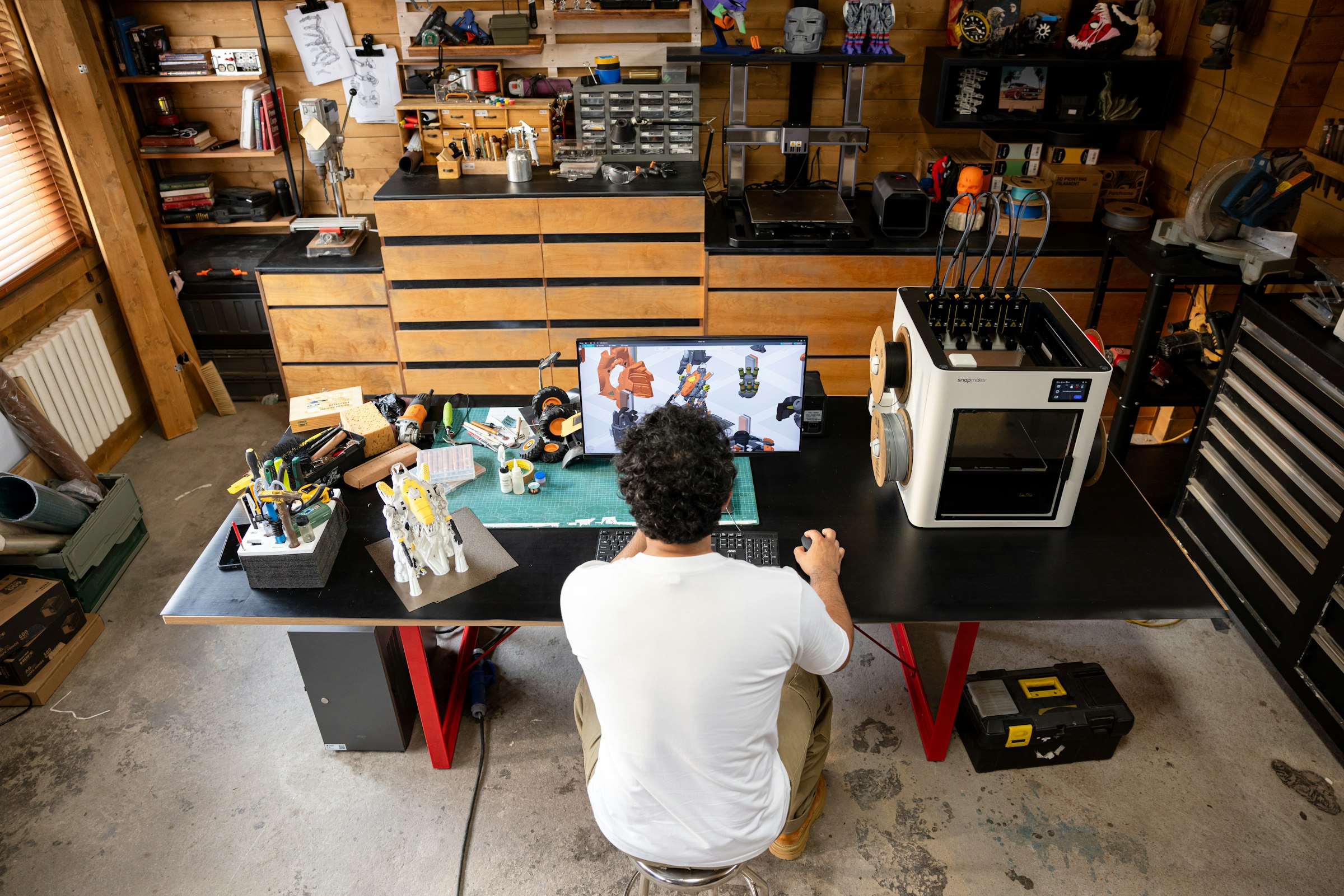 Inventor working at a desk beside a 3D printer