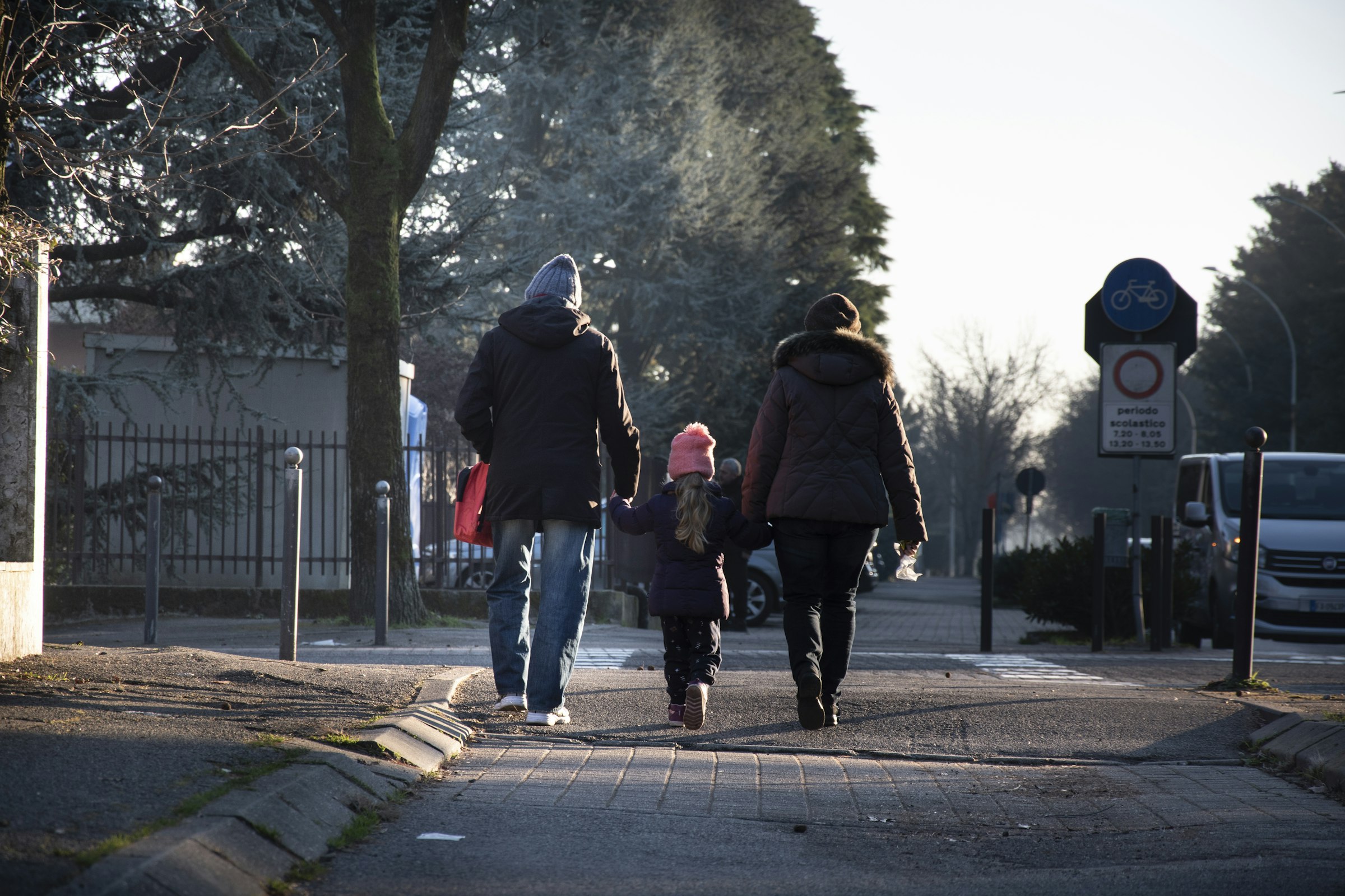 Parents and child walking hand in hand down a street