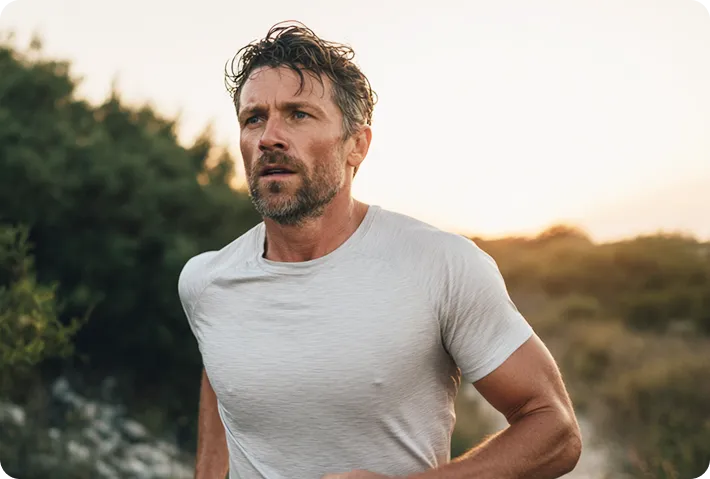 Man with tousled hair running outdoors at sunset