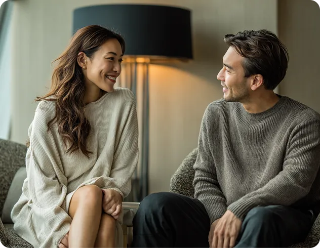 Two people smiling during a conversation indoors.