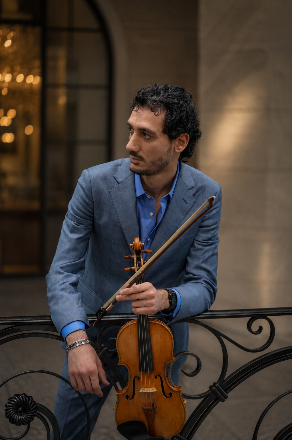 Nick Kelian holding a violin by an elegant railing