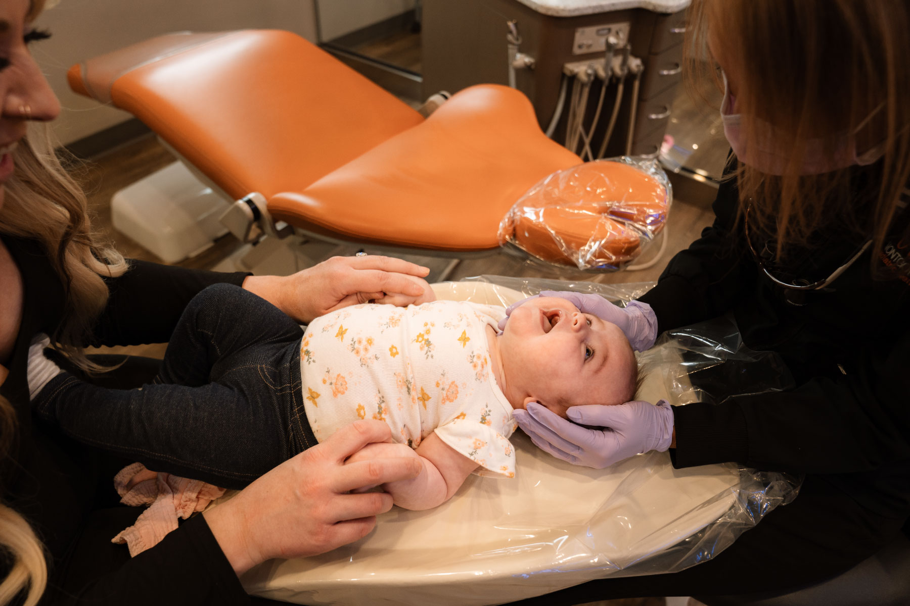 baby happily being examined by doctor while mom holds hands