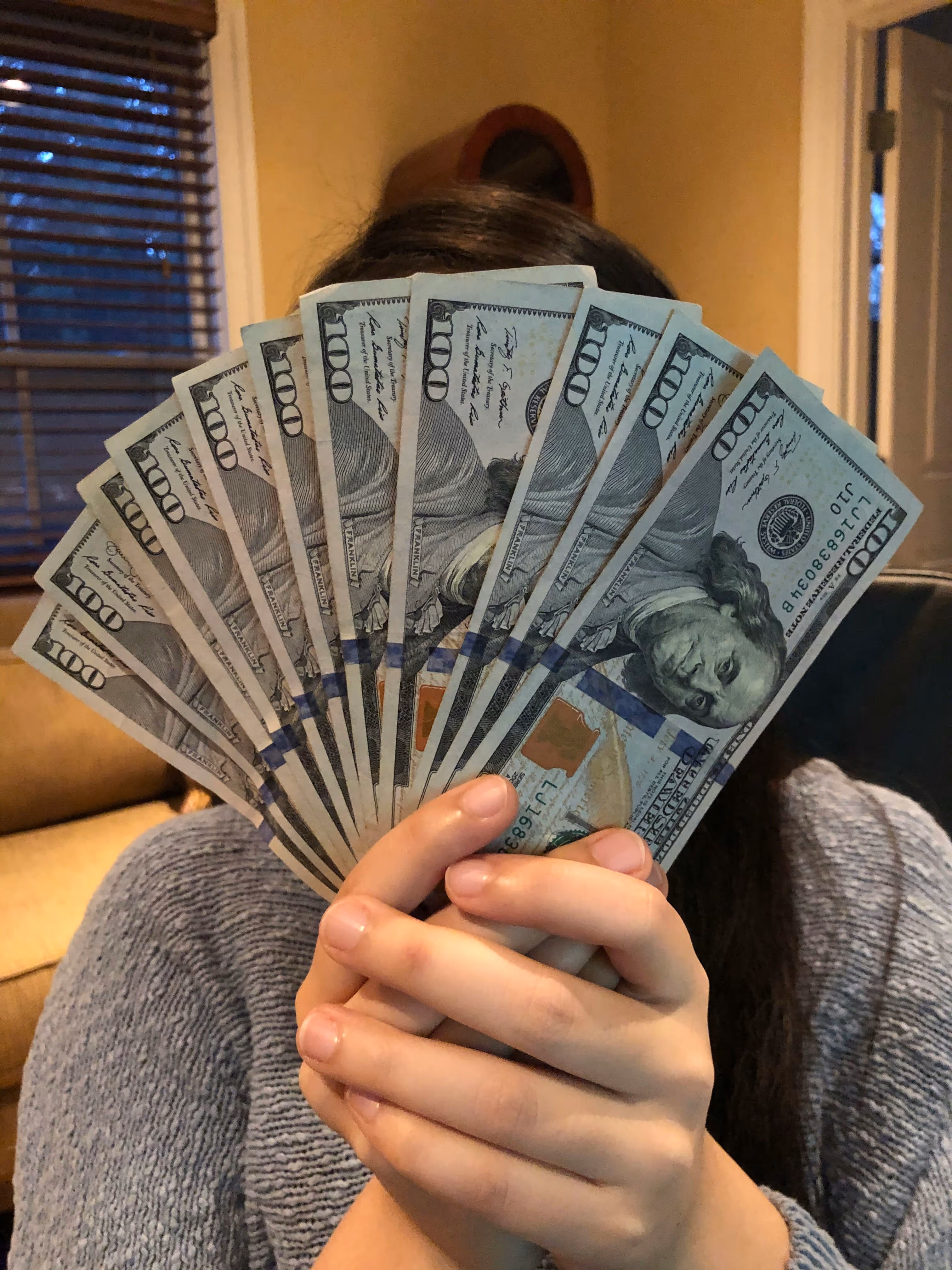 A woman holding a fan of US dollar bills.