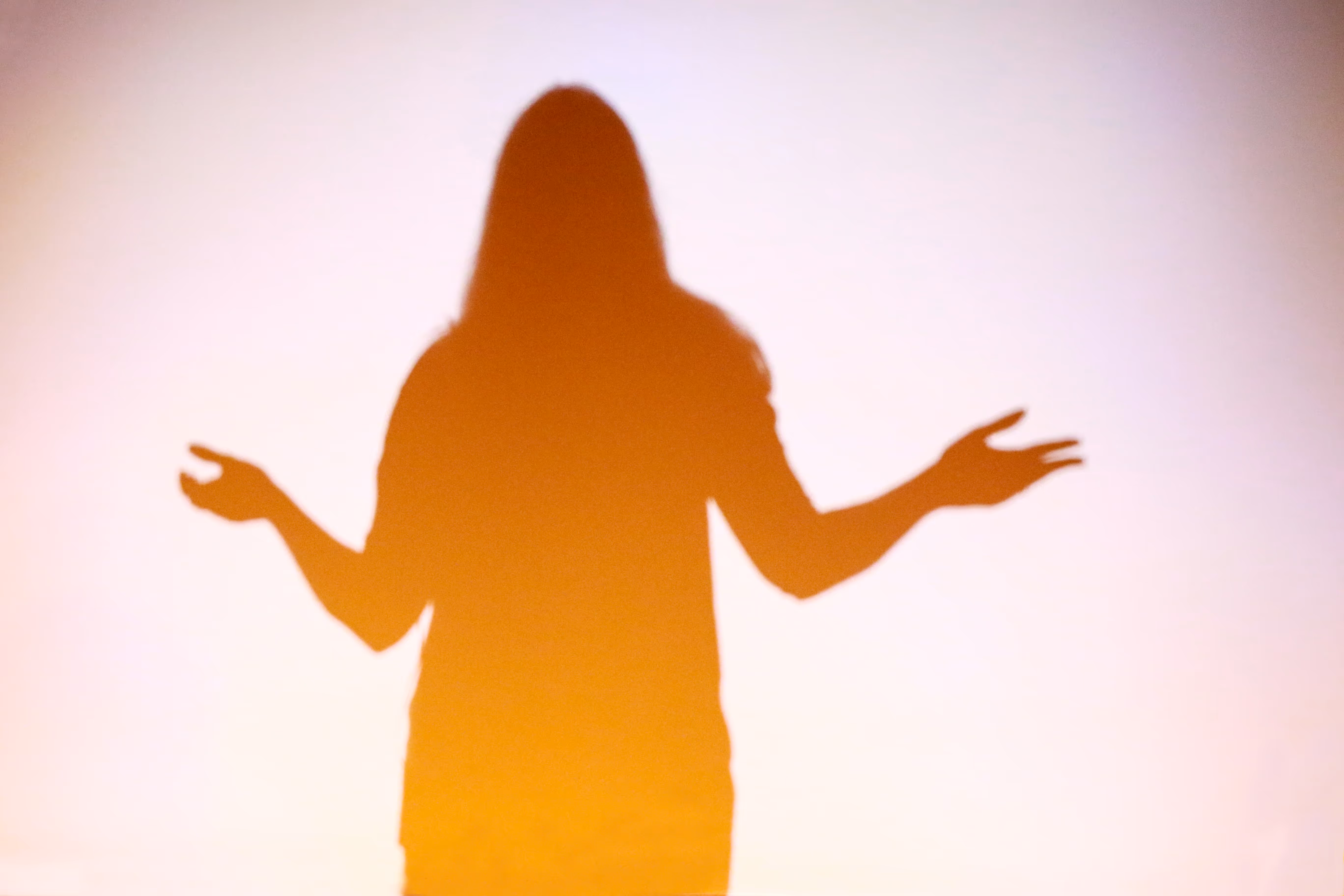 Silhouette of a woman standing with arms outstretched against a gradient background.