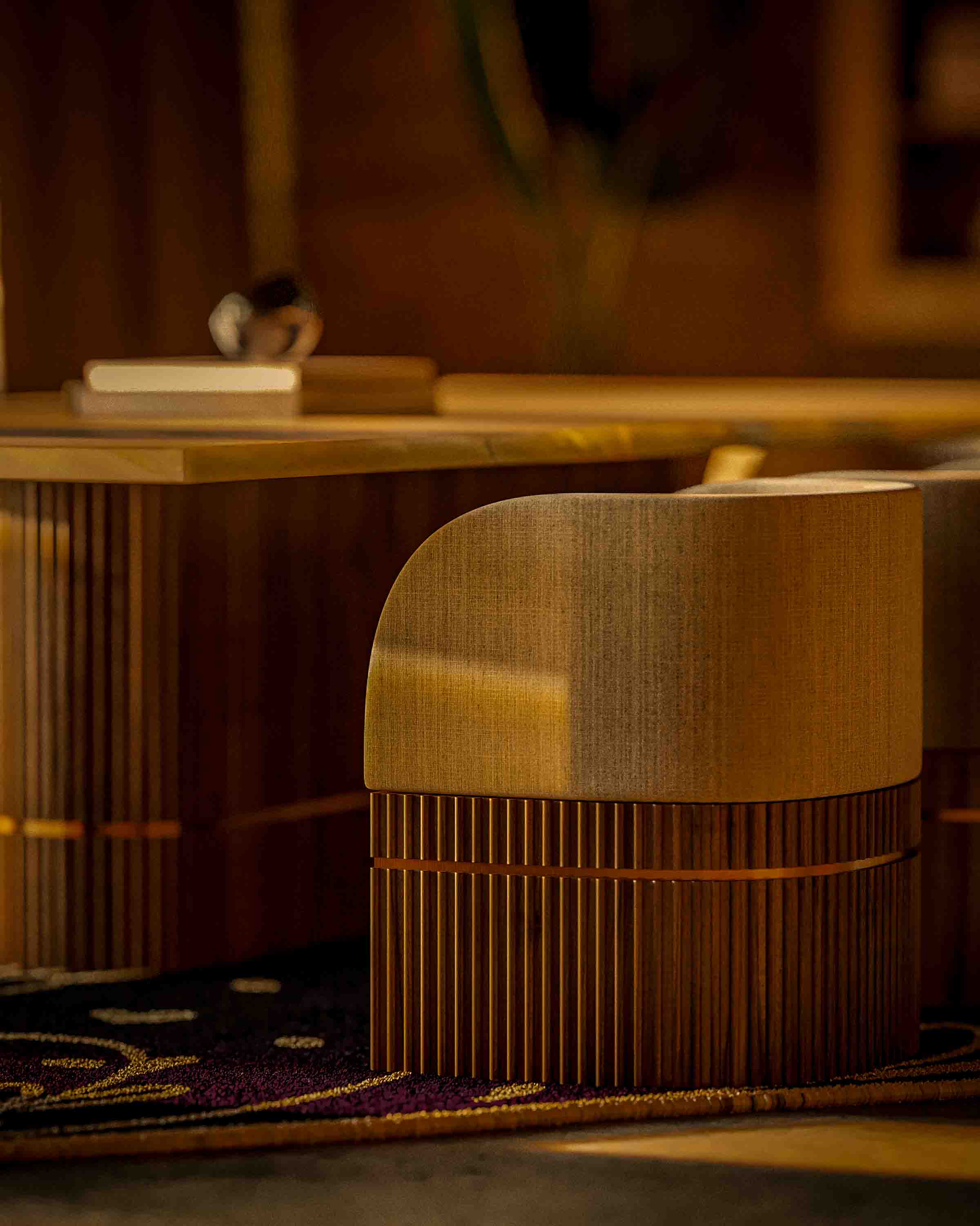 Close-up of a modern wooden chair with a fabric backrest next to a matching table in warm lighting.