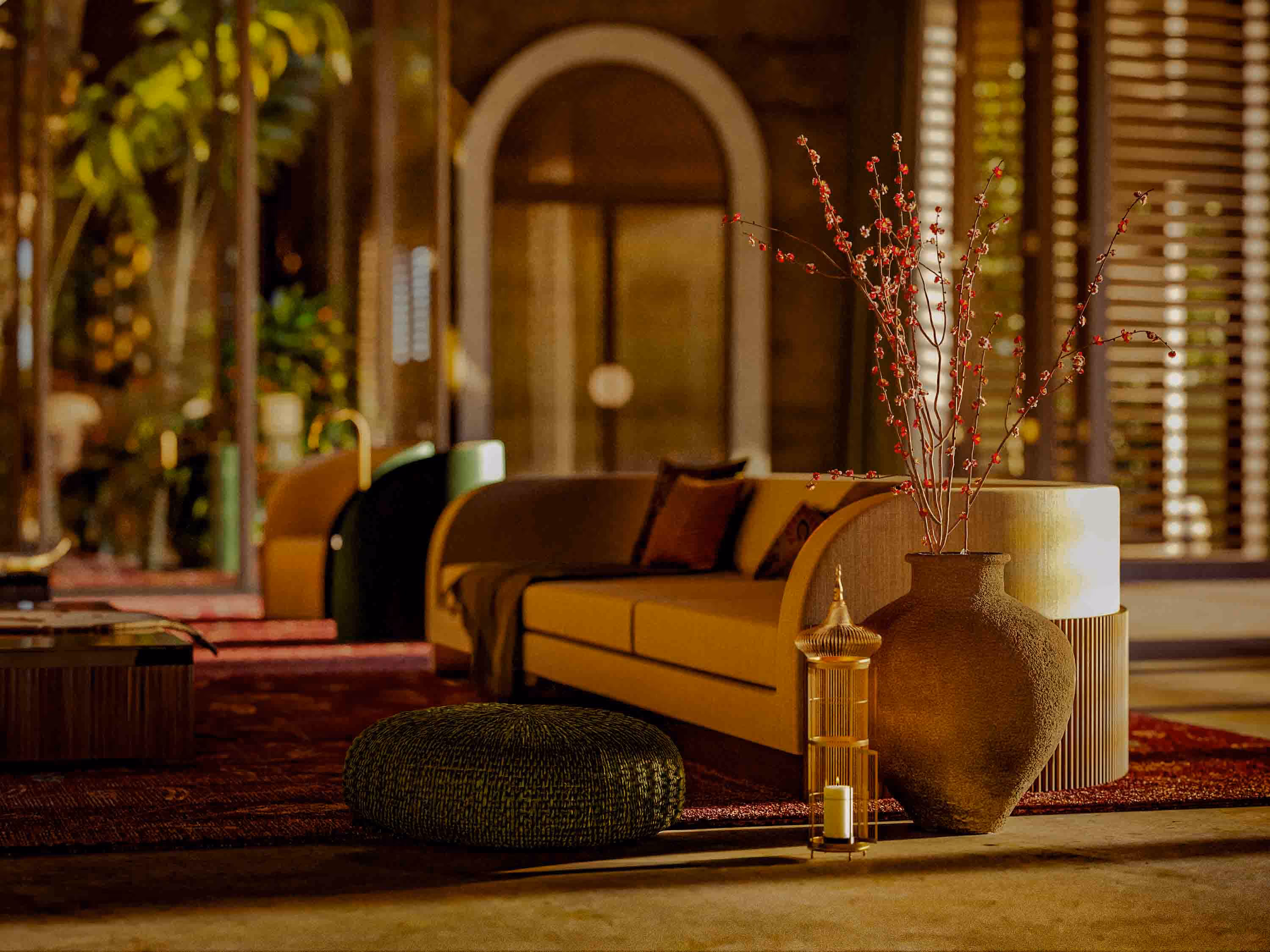 Cozy living room with a beige sofa, decorative cushions, a large textured vase with red branches, and a low round cushion on a patterned rug.