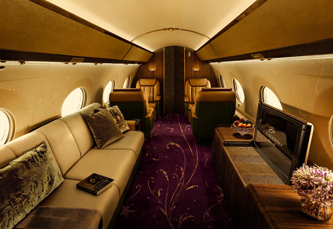 Luxurious private jet interior with beige sofa, leather seats, patterned purple carpet, and flat-screen TV.