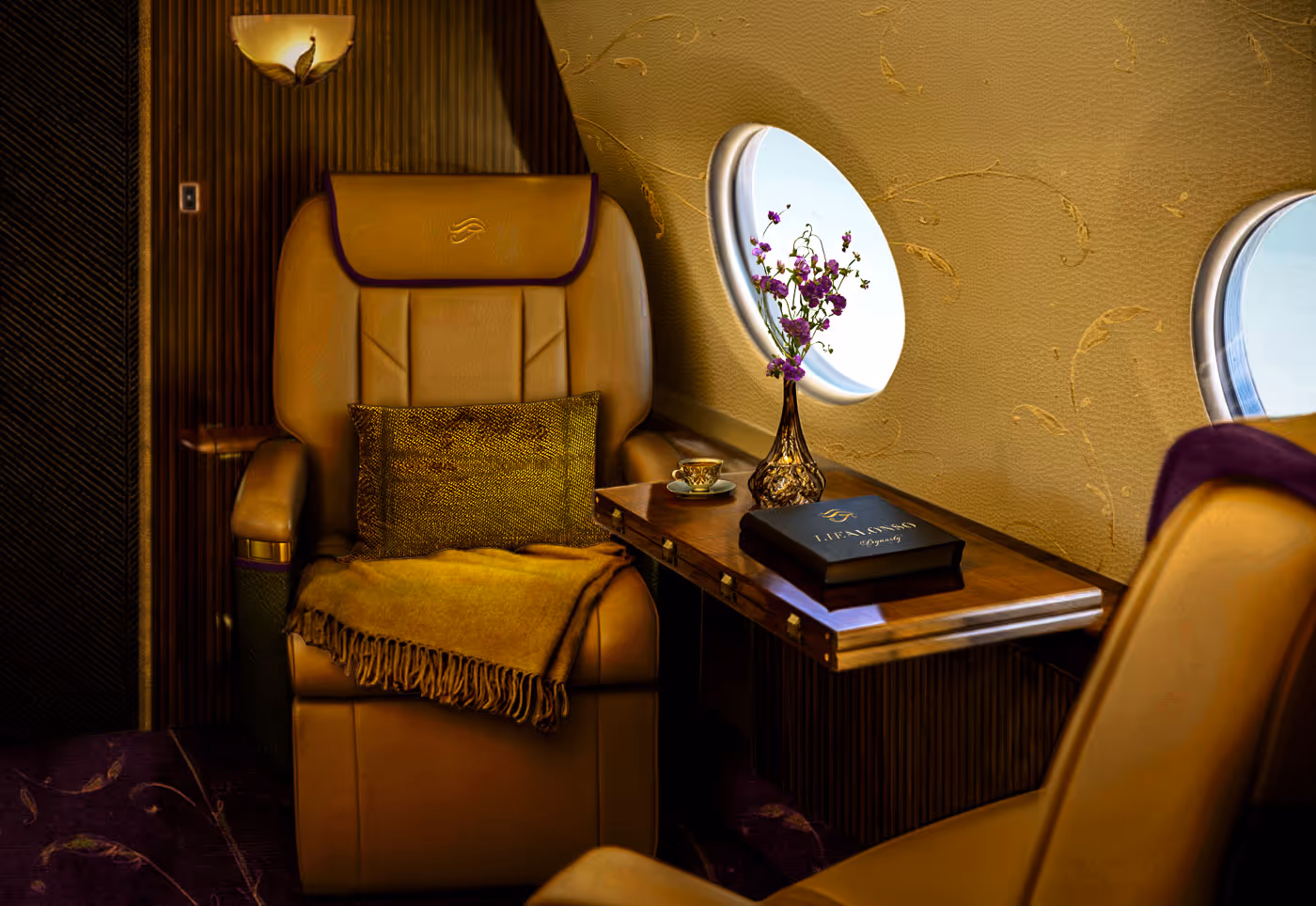 Luxurious tan leather airplane seat with golden throw blanket and pillow beside a wooden table holding a flower vase and a book near two airplane windows.