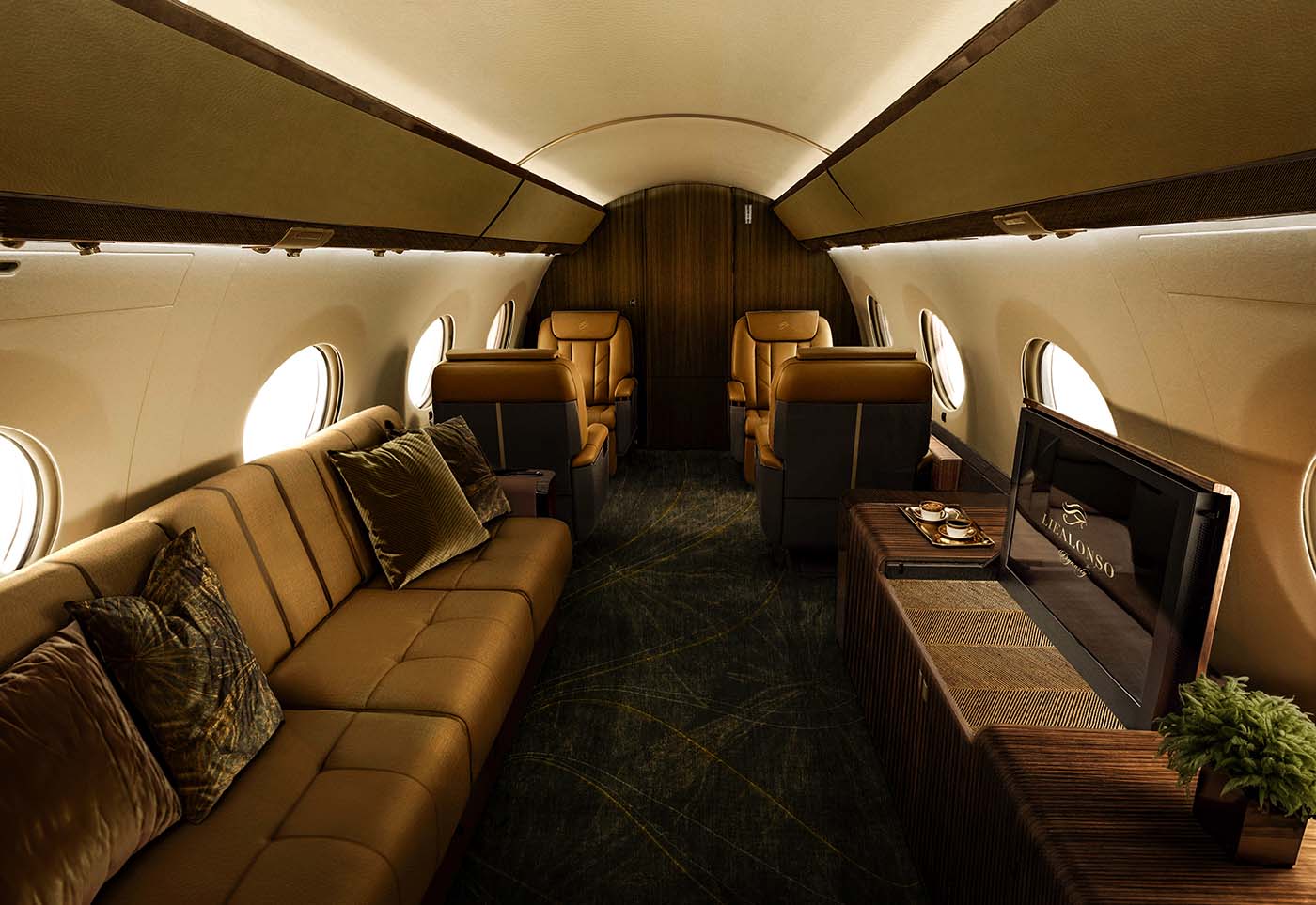 Luxurious Lie Alonso private jet interior Café Suave. Featuring tan leather seating, a long couch with pillows, a built-in TV, and wooden accents.