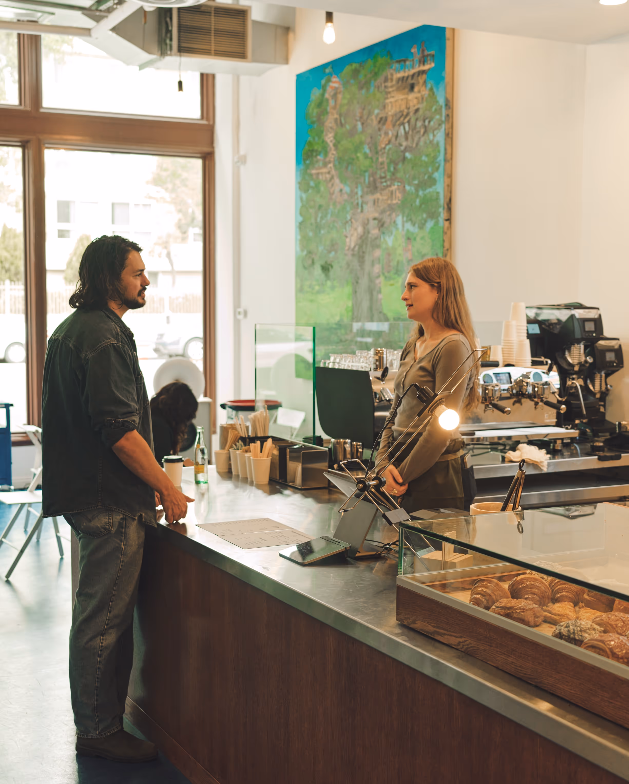 A coffee shop with a customer talking to barista