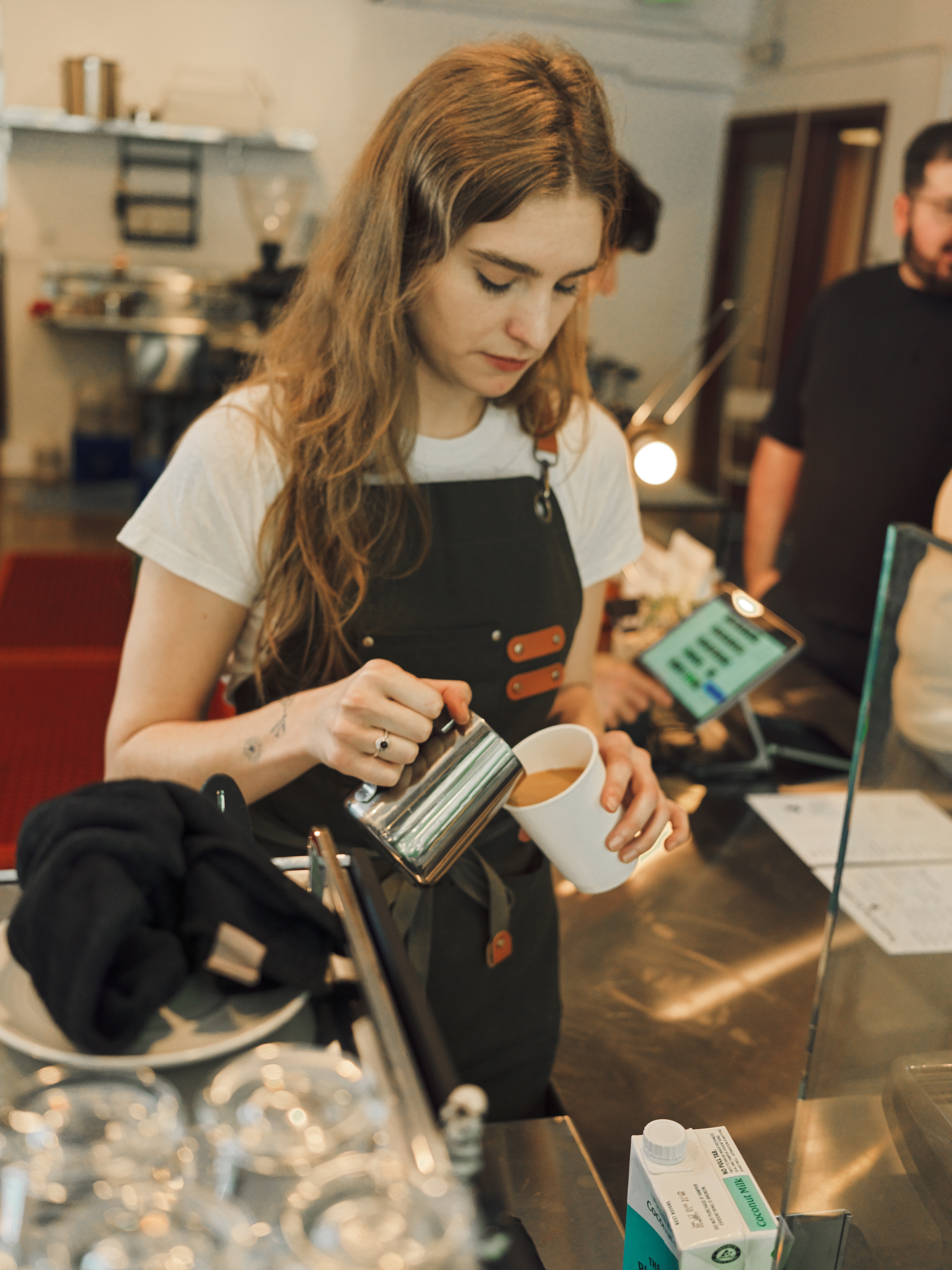 A barista pouring steamed milk into a cup at the MacArthur Park bar