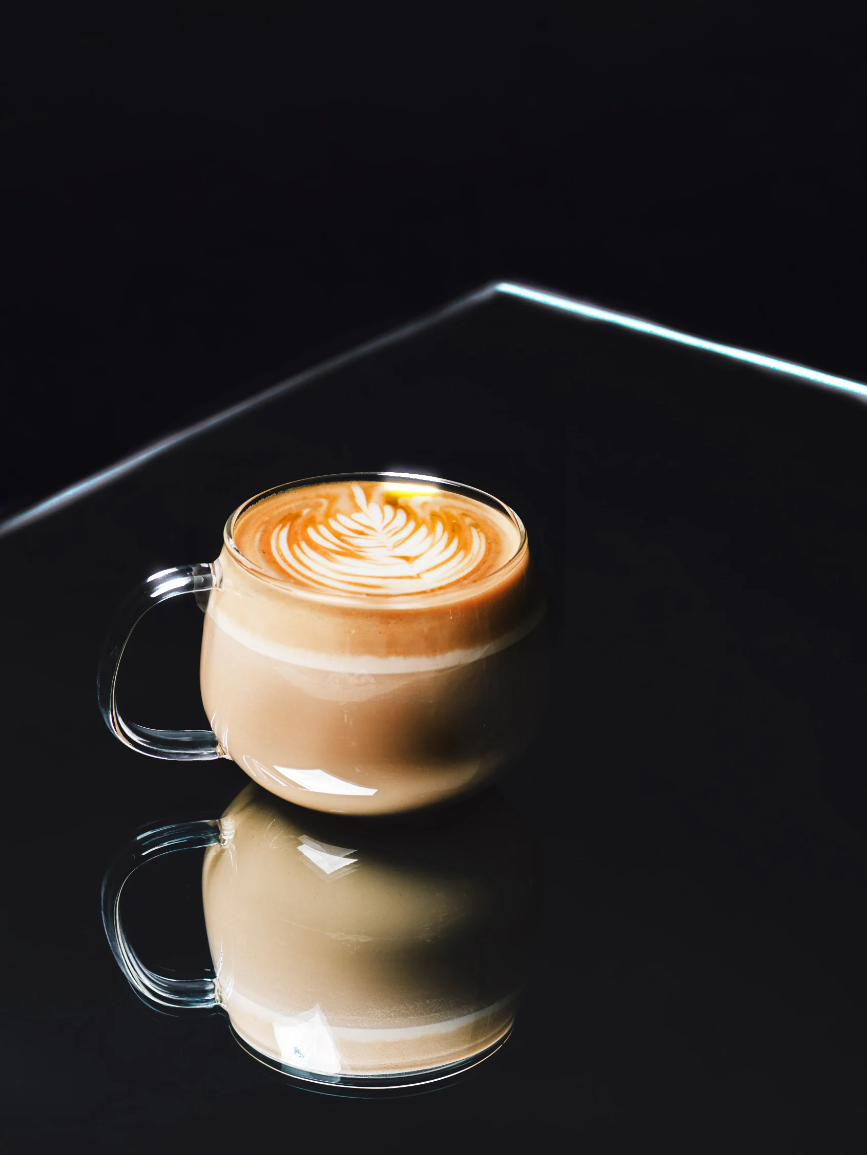 Latte: espresso with properly textured milk and latte art, in a clear glass cup