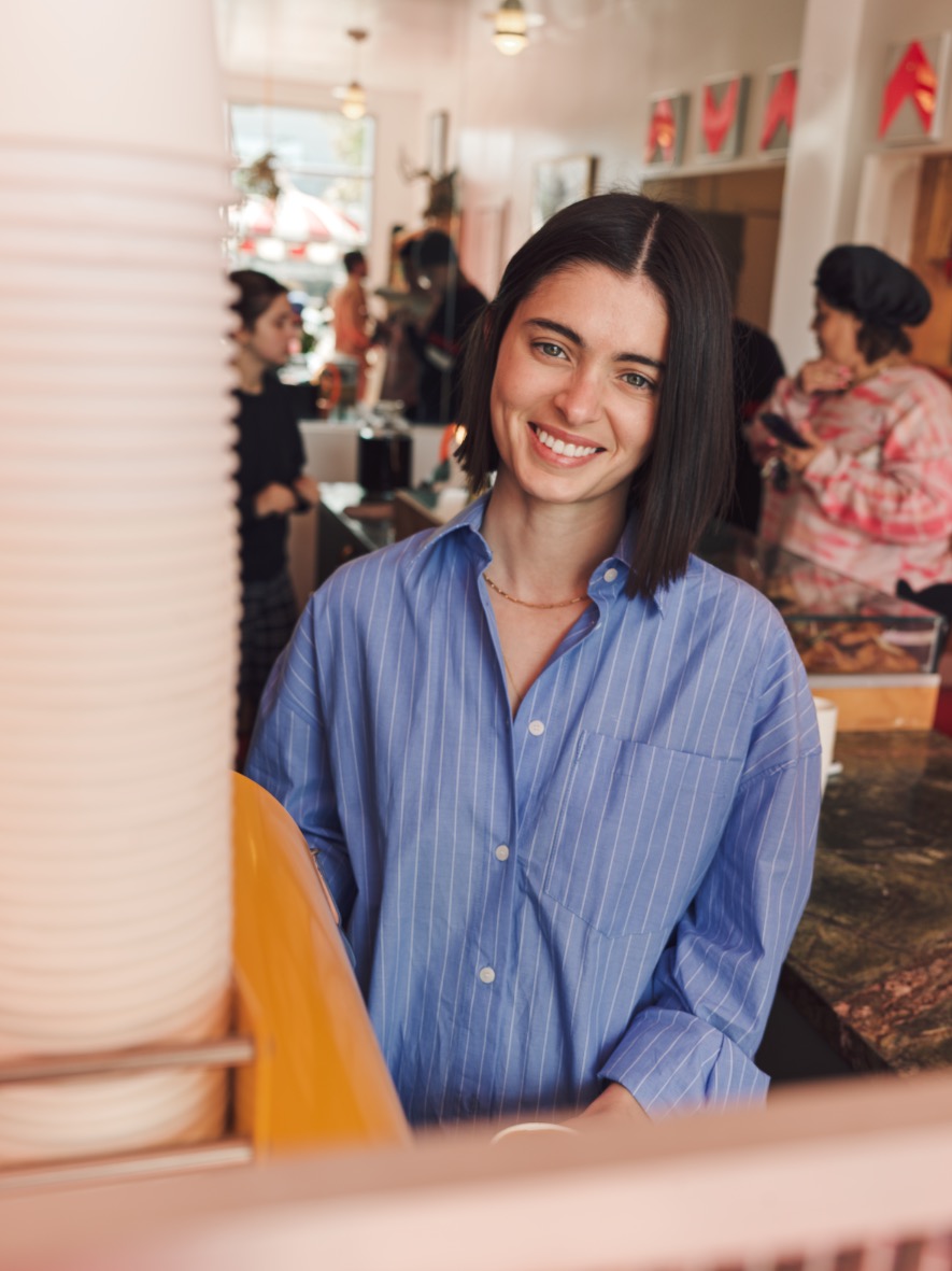 Barista smiling behind the counter at Jurassic Magic's Mid-City coffee shop